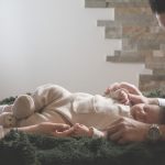 A touching family scene showing parents lovingly interacting with their newborn baby indoors.